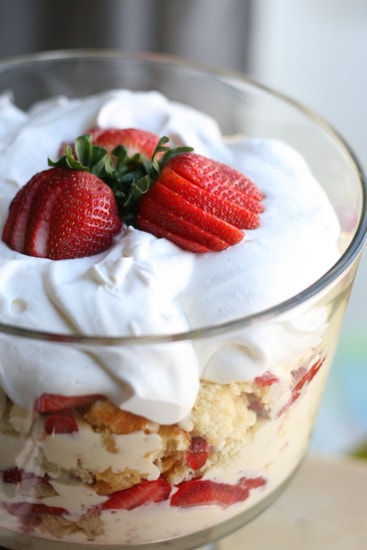 Strawberry Trifle in a glass dish topped with whipped cream and strawberries. 