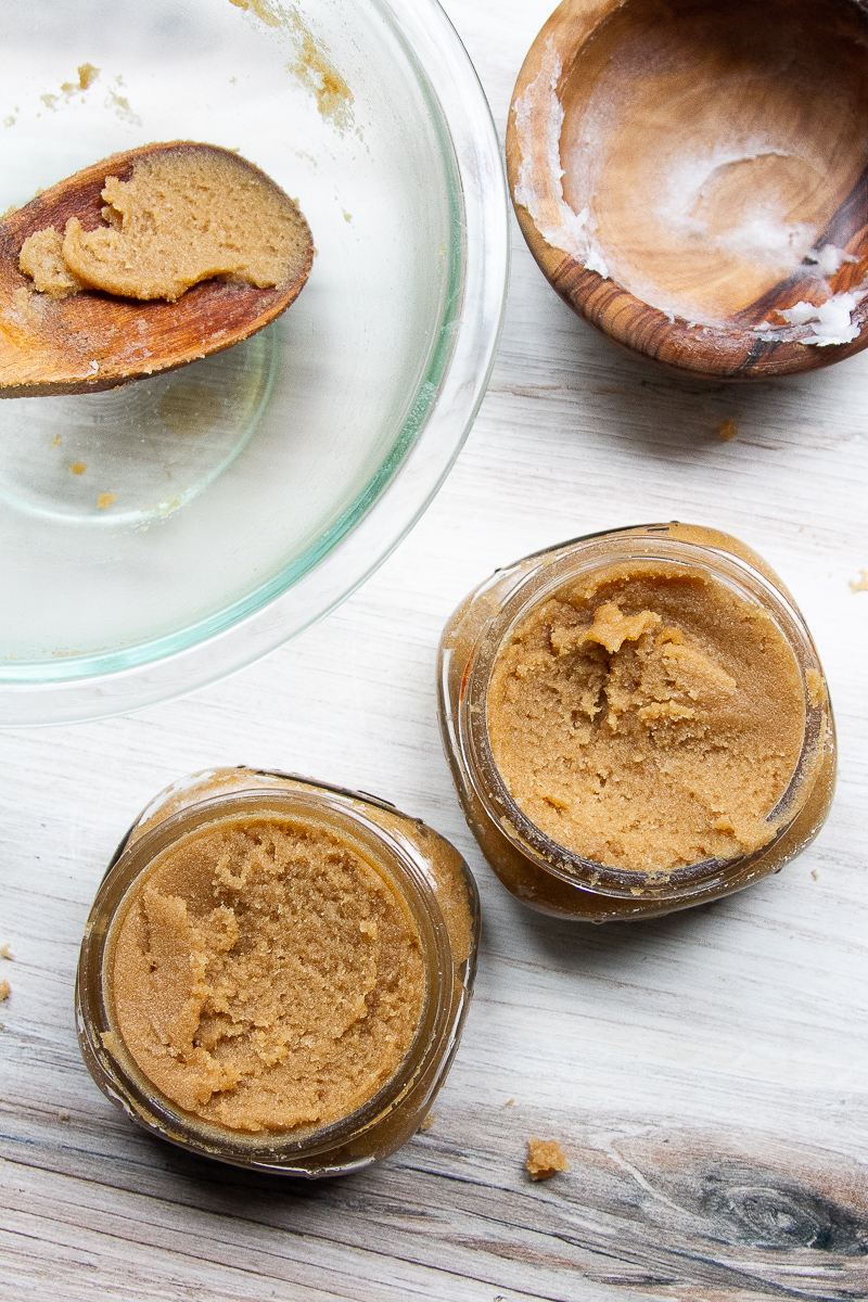 Brown sugar scrub transferred to two small mason jars.