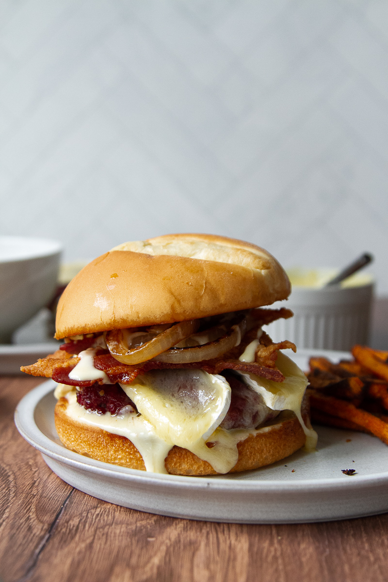 Burger with melted brie, maple aioli, bacon, and grilled onions.