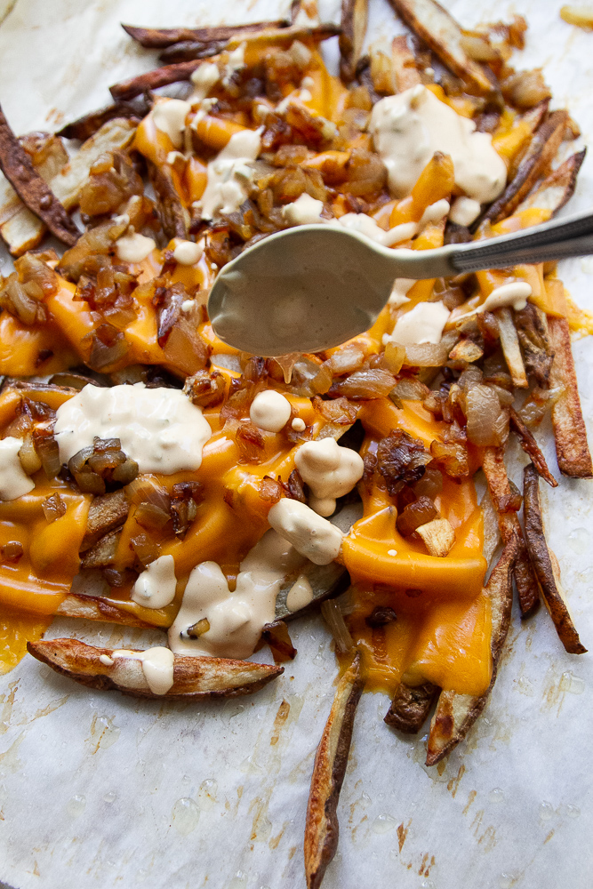 Drizzling burger sauce on top of the finished fries.