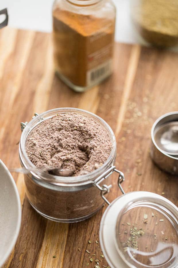 The BEST homemade taco seasoning recipe out there. Honest. And you can tweak it to make it paleo, Whole30 compliant, or keto/low-carb friendly! perrysplate.com #tacoseasoning #homemadetacoseasoning #glutenfree Finished taco seasoning in a small glass canning jar on a wooden cutting board.