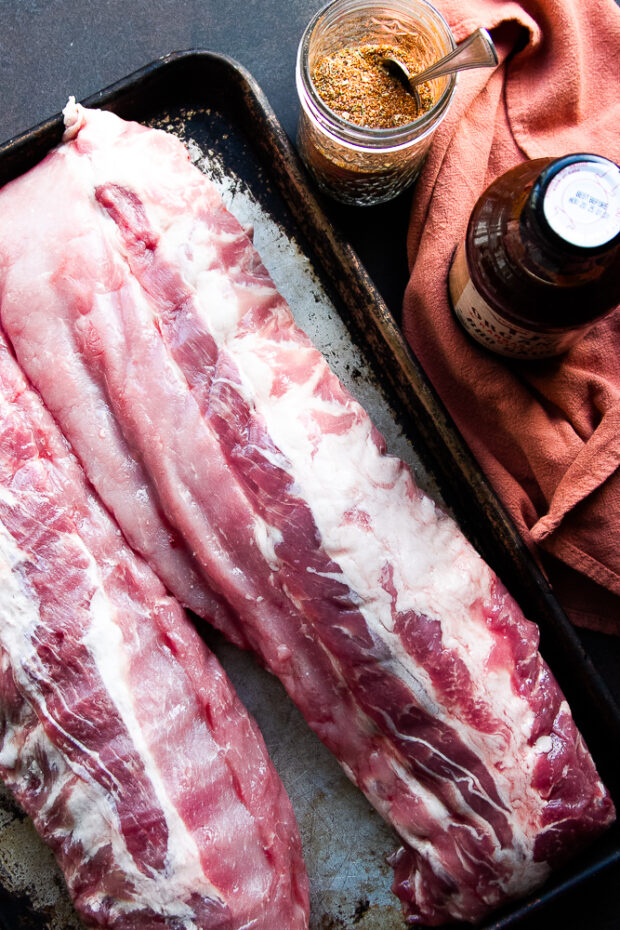 Ingredients for Instant Pot Pork ribs: racks of pork ribs, steak/BBQ rub, and BBQ sauce.