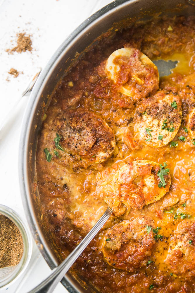 Egg Curry in a pan sprinkled with spices and coconut milk.