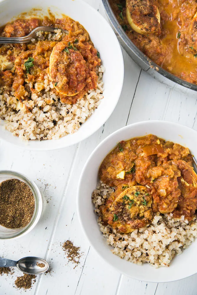Egg Curry is delicious served with cauliflower rice. Egg curry served in two bowls with roasted cauliflower rice and sprinkle of garam masala.