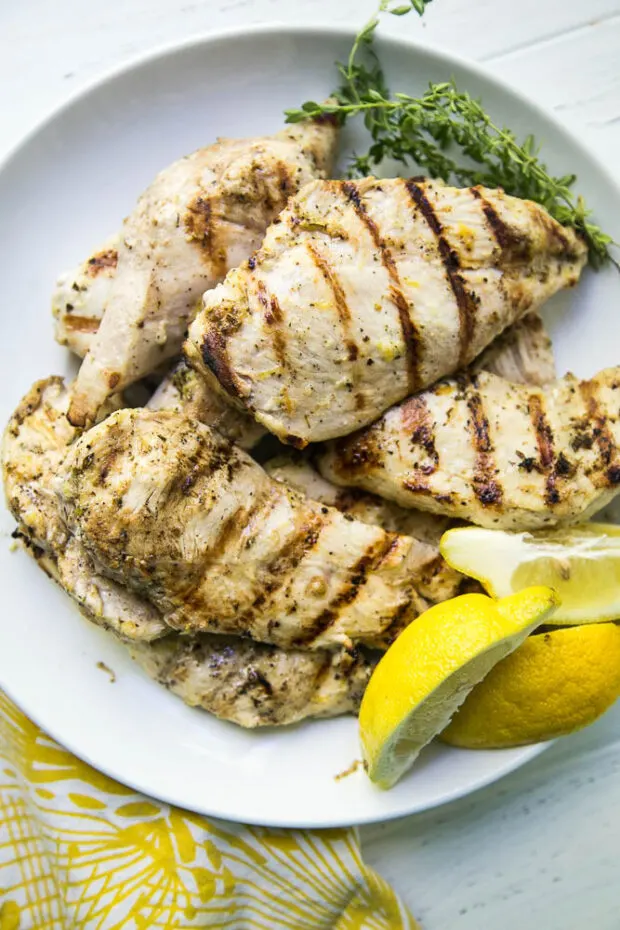 The Best Lemon Grilled Chicken on a platter with fresh lemons as garnish.