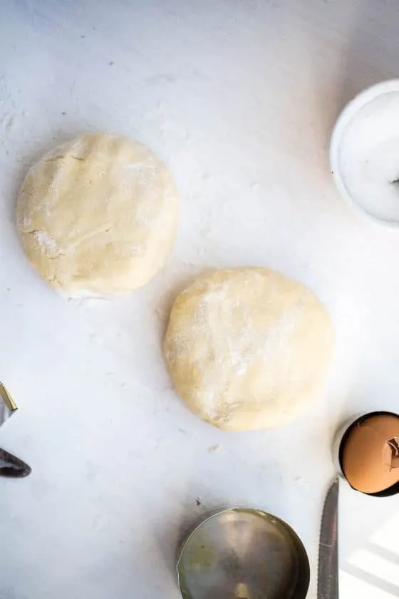 Gluten-Free pie crust dough formed into two discs and dusted with flour. 