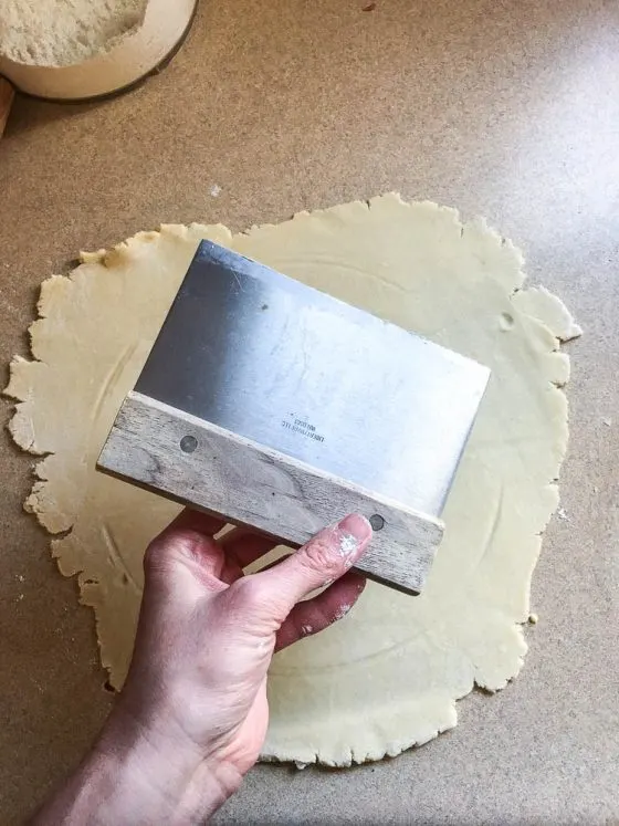 Perfect Gluten-Free Pie Crust -- Even better than most traditional pie crusts! | perrysplate.com | gluten-free recipes | gluten-free baking View of a pastry scraper held over the rolled out pie crust dough.