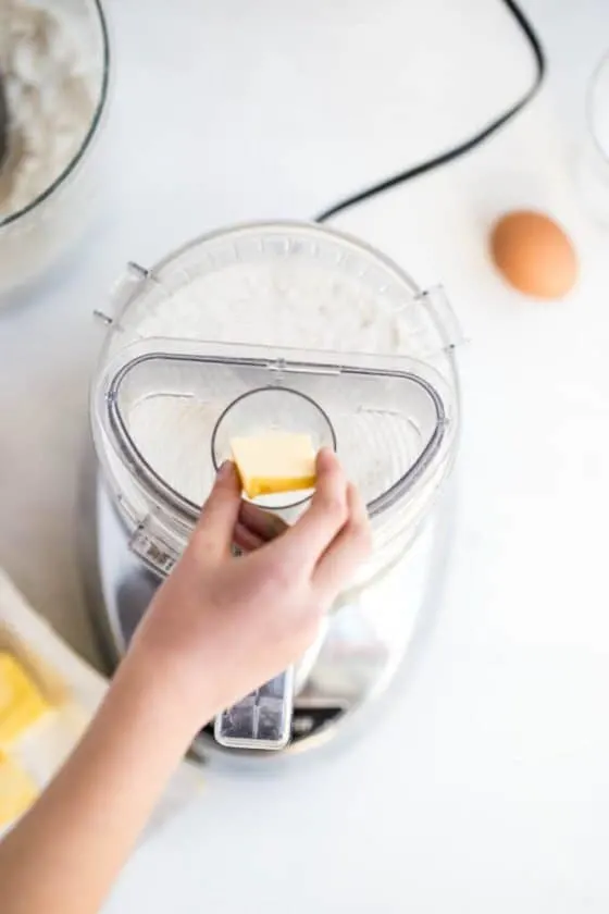 Adding cold butter to the gluten-free flour to make the pie crust dough. 