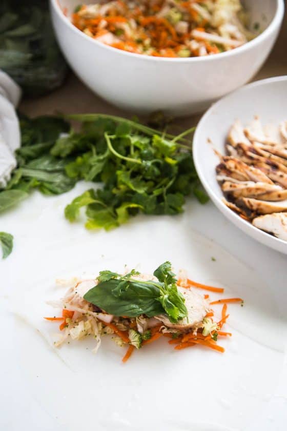 A softened rice wrapper with chicken and veggies in the center ready to roll.