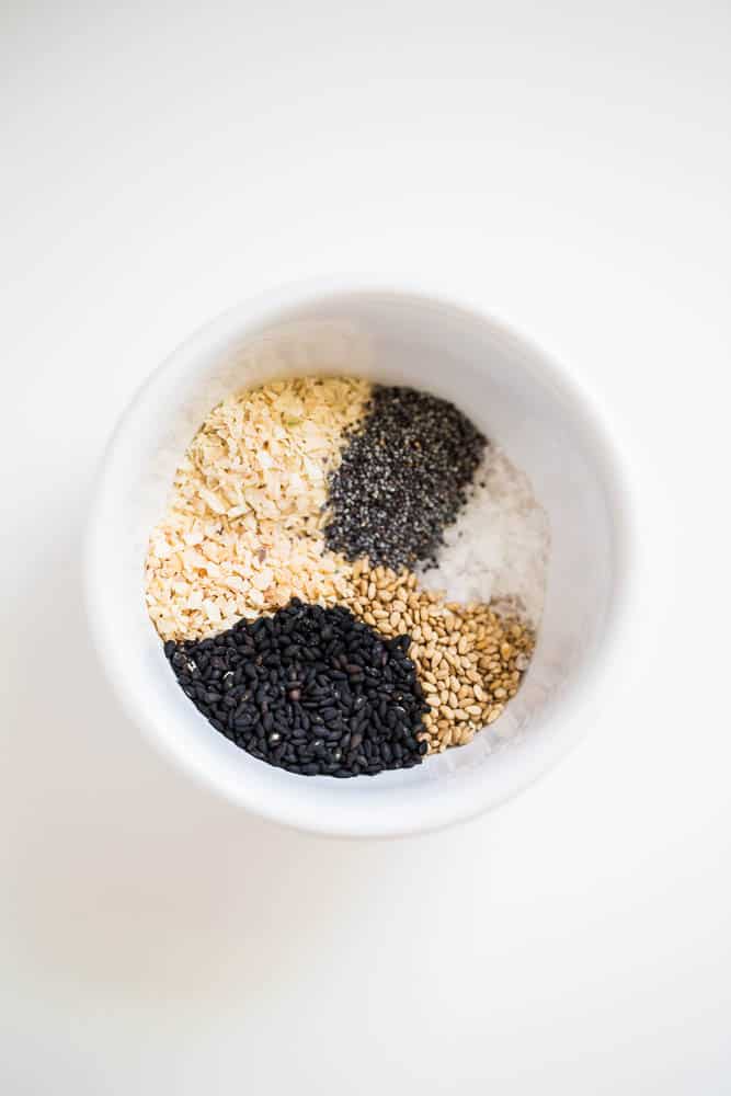 How to Make Everything Bagel Seasoning -- a knock off of the Trader Joe's version! It's so easy to make and once you start sprinkling, you won't be able to stop! | perrysplate.com A bowl with the six ingredients for the recipe, but have not yet been mixed together.