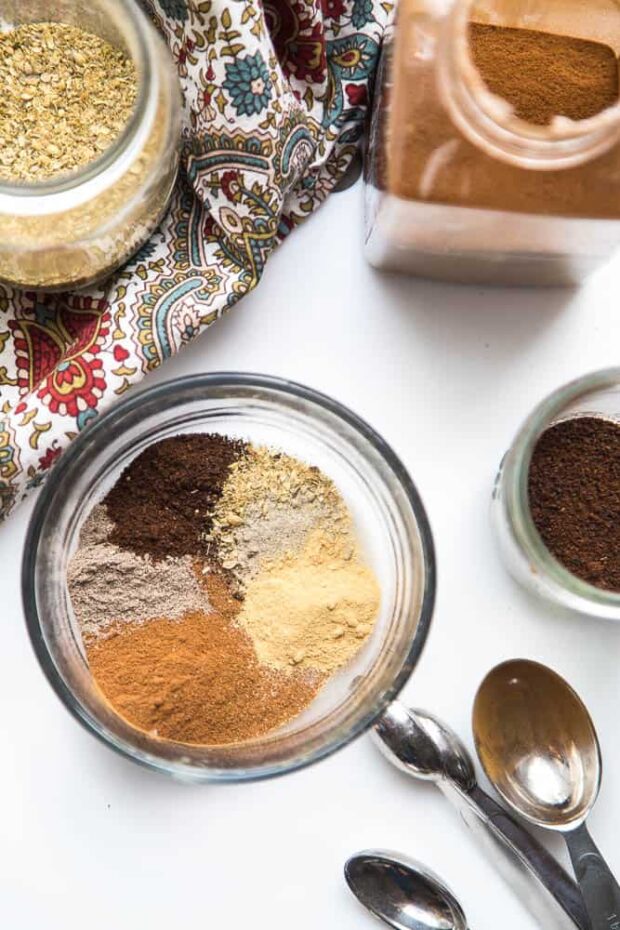 A glass jar with the ingredients to Chai Spice Blend that aren't mixed together yet.