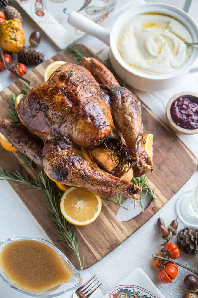 Finished roasted Turkey on a platter with a table ready for Thanksgiving dinner.