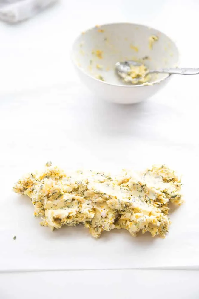 Blended herb butter placed on a piece of parchment paper.