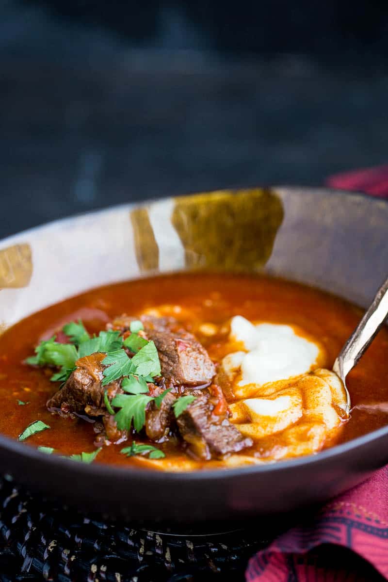 Paleo Hungarian Goulash in a earth-toned bowl served over cauliflower mash and garnished with fresh parsley.