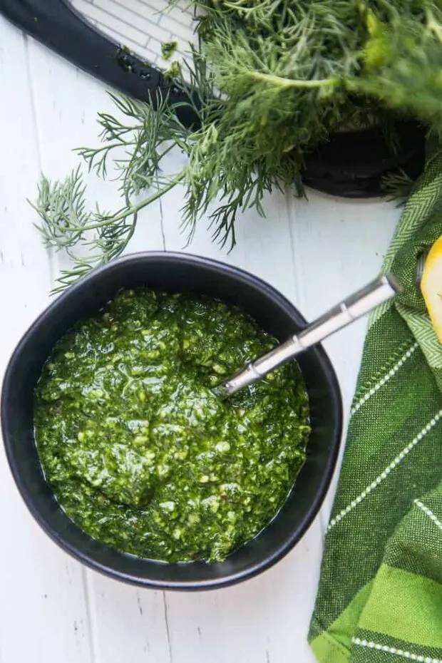 Bowl of pesto (dill pesto) in a black bowl next to a green napkin.