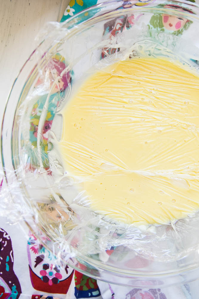 Pressing plastic wrap on custard keeps skin from forming while it's cooling in the fridge. 