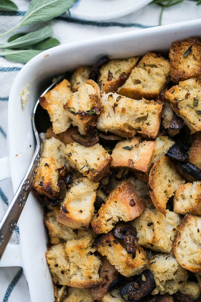 Stuffing made with sourdough bread is the best! This version has roasted garlic, roasted mushrooms, and salty pancetta mixed in. Perfect for a classic Thanksgiving side. | perrysplate.com