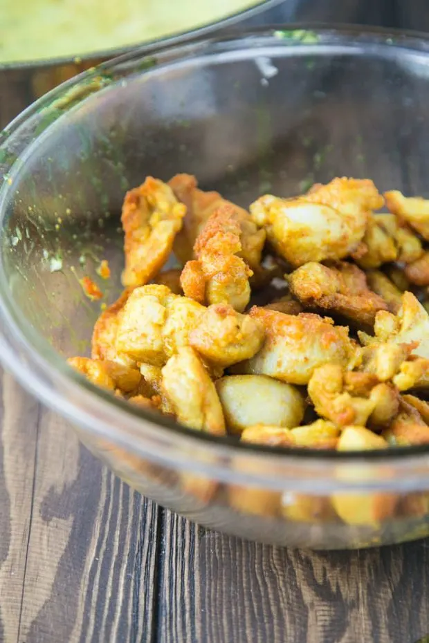 Toasting the turmeric-covered chicken adds a lot of flavor to the curry. Chicken shown in a glass bowl after being browned in cooking oil.