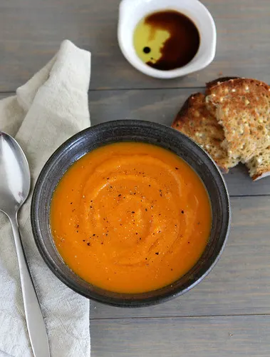 Roasted Butternut Squash Soup | Paleo Meal Plans Bowls of Butternut Squash Soup with Carrot & Ginger and a side of garlic bread.