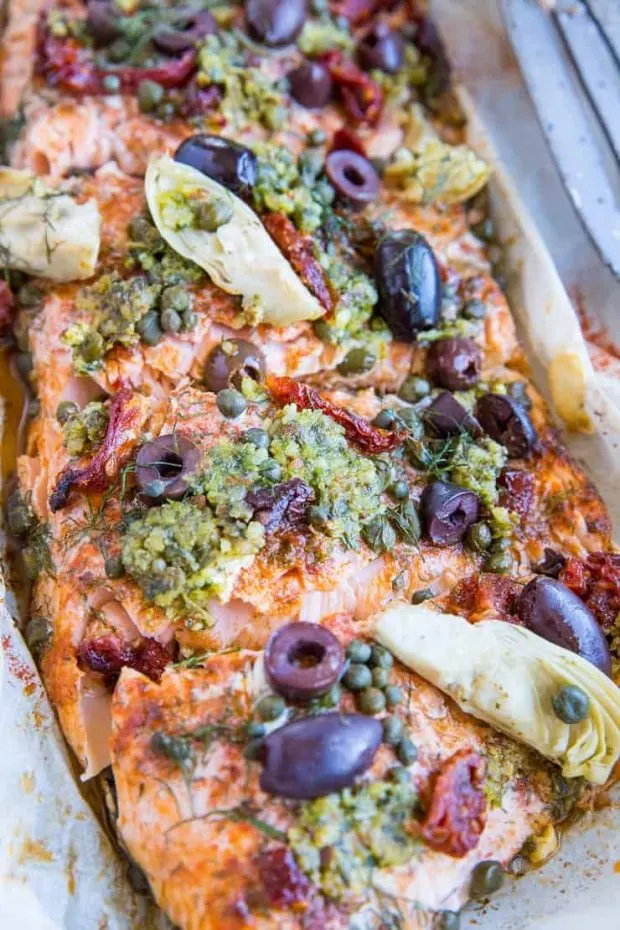 Salmon in parchment covered with Mediterranean-inspired toppings like basil pesto, artichoke hearts, kalamata olives, capers, and sun-dried tomatoes.