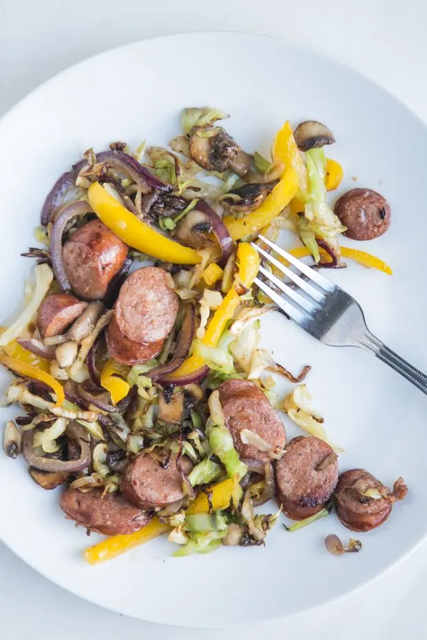 Sausage Skillet meal cooked and on a white plate with a fork ready to eat.