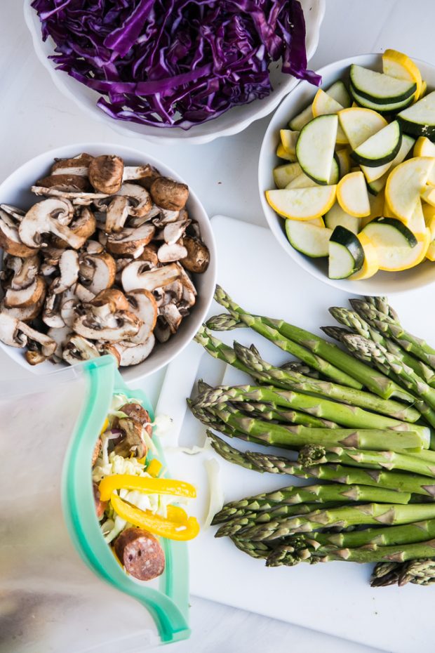 Prepped bowls of shredded cabbage, sliced mushrooms, sliced summer squash, chopped asparagus