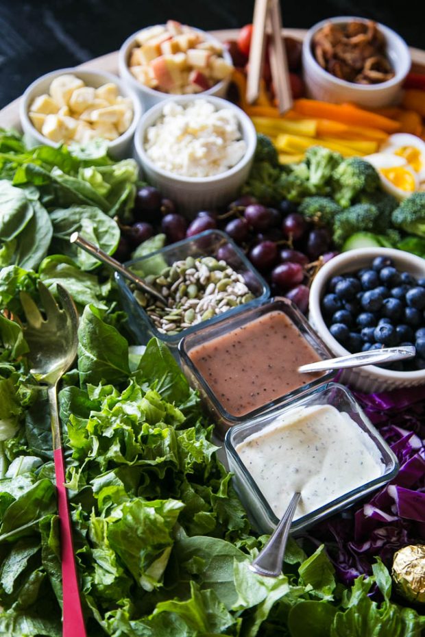 Charcuterie board filled with colorful vegetables and salad dressing in little containers.