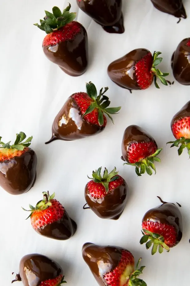 Freshly dipped strawberries on parchment paper, still wet.