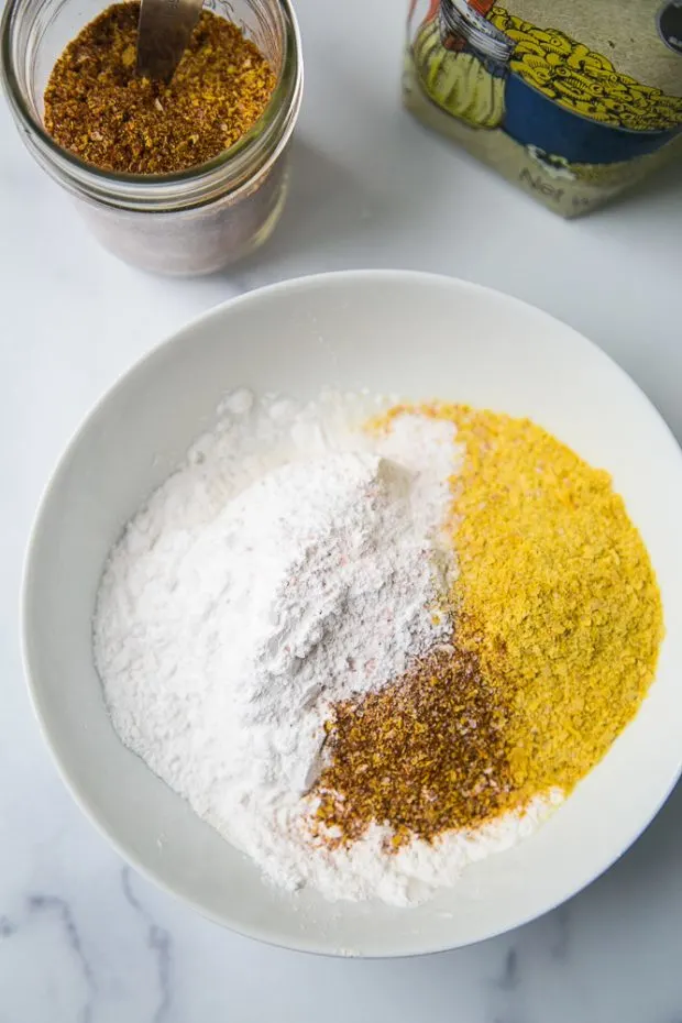 A white bowl with the gluten free breading ingredients -- tapioca flour, cassava flour, nutritional yeast, taco seasoning, and salt.