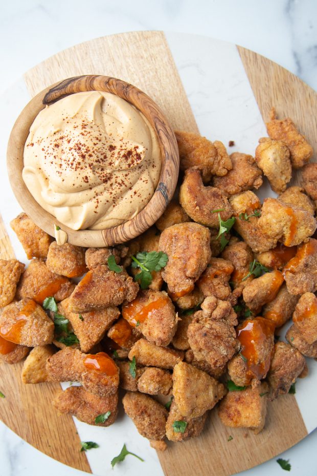 Wooden board with fiesta gluten free chicken nuggets and vegan queso sauce.