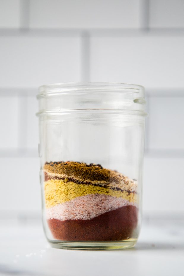 Homemade taco seasoning spices layered in a mason jar to resemble sand art. 