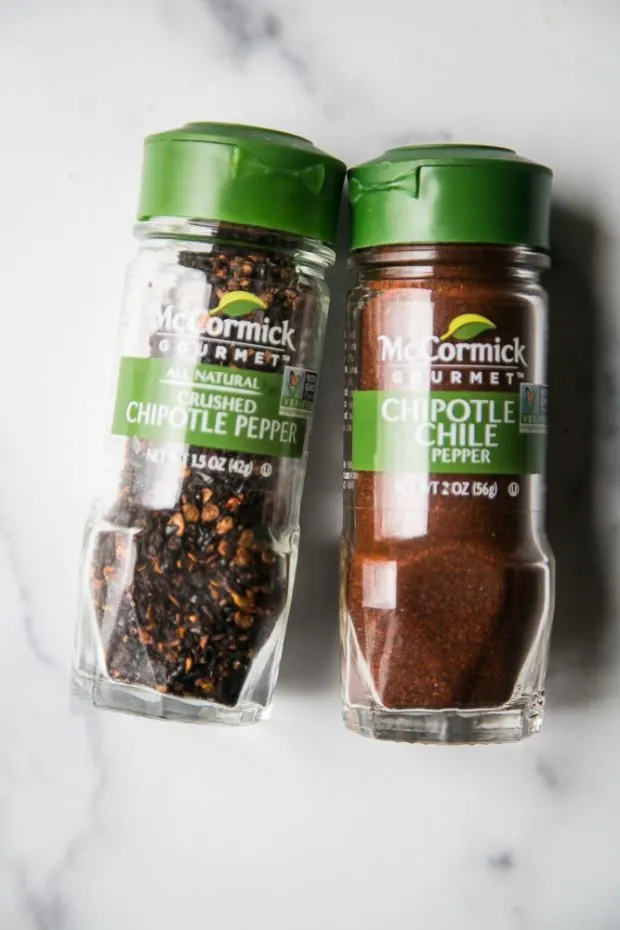 Small spice jars of chipotle chile powder and crushed chipotle peppers. 