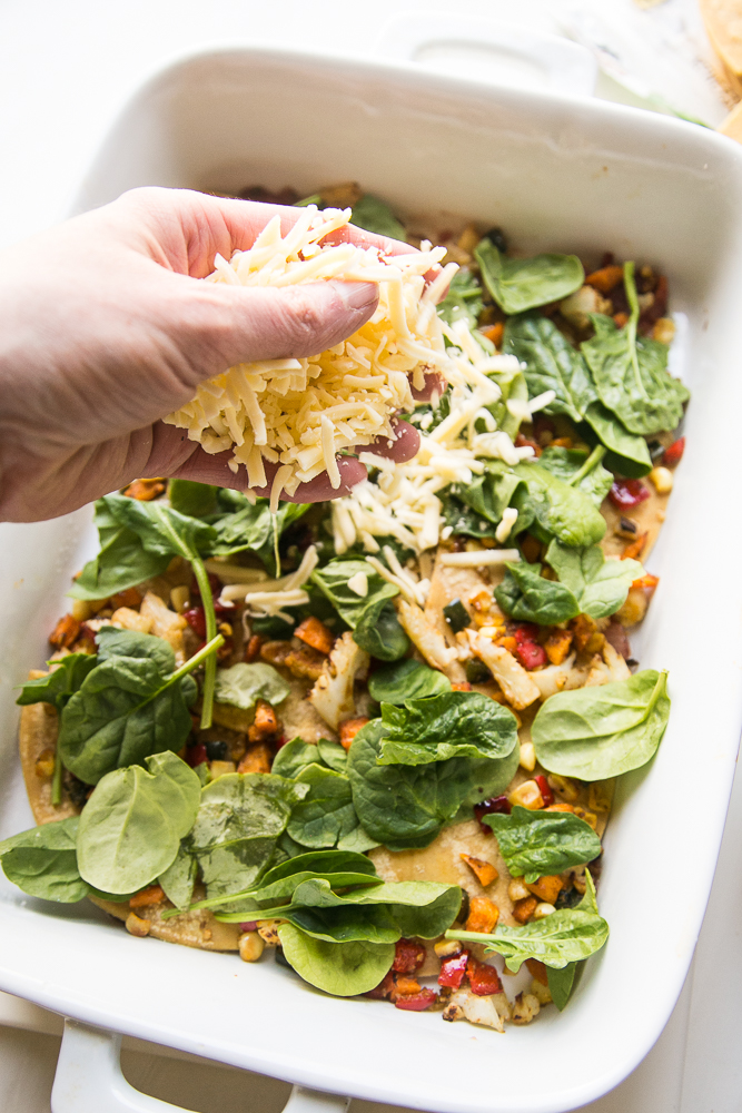 Layering cheese and spinach for Stacked Roasted Vegetable Enchiladas