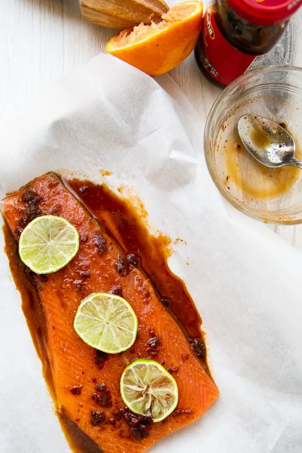 Sweet Chipotle Salmon prepped on a piece of parchment with lime slices on top.