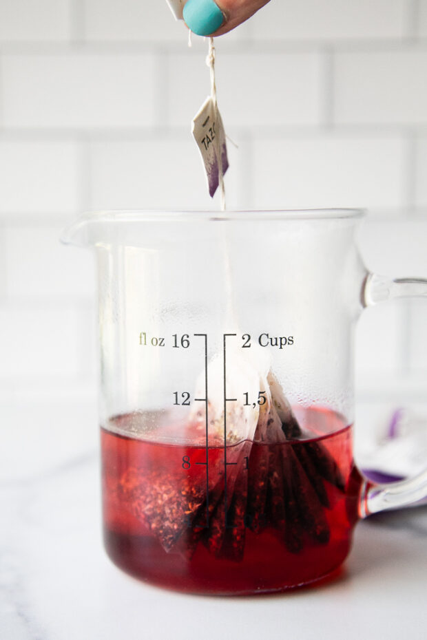 Tazo Passion Tea bags steeping in a cup of water to create a concentrated tea.