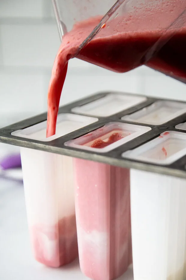Pouring the tea blended with the frozen strawberries into the popsicle molds.