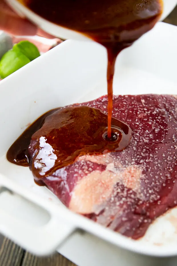 Pouring the steak fajita marinade over a salted flank steak.