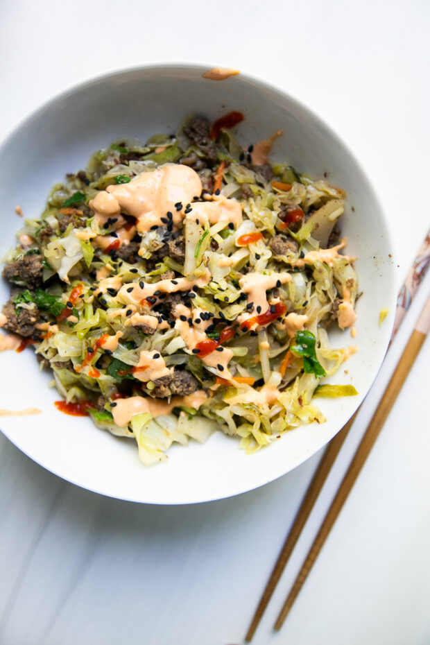 Egg Roll in a Bowl with ground beef topped with sriracha mayo and black sesame seeds. Easy paleo recipe.