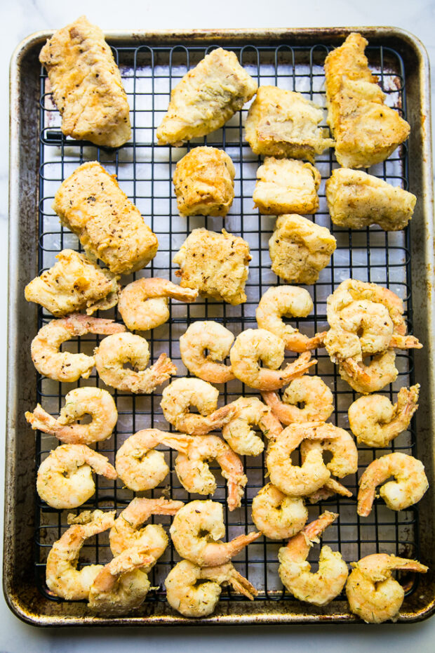 Breaded & pan-fried cod pieces and shrimp ready to eat! I use a cooling rack on top of a rimmed baking sheet to help the breading stay crisp.