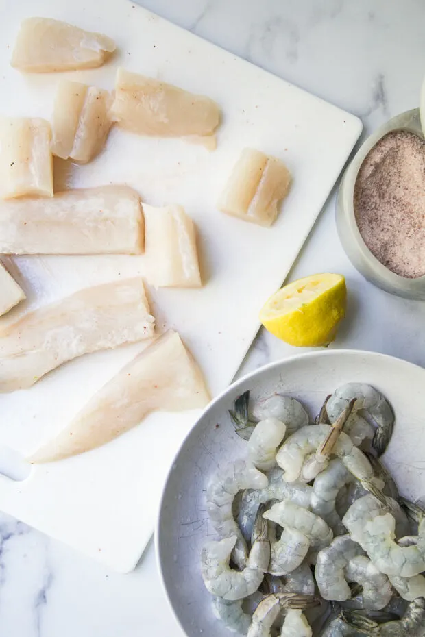 Cod fillet pieces and shrimp that have been salted and are resting.