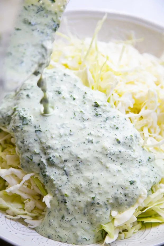 Pouring the yogurt dressing over the cabbage slaw.