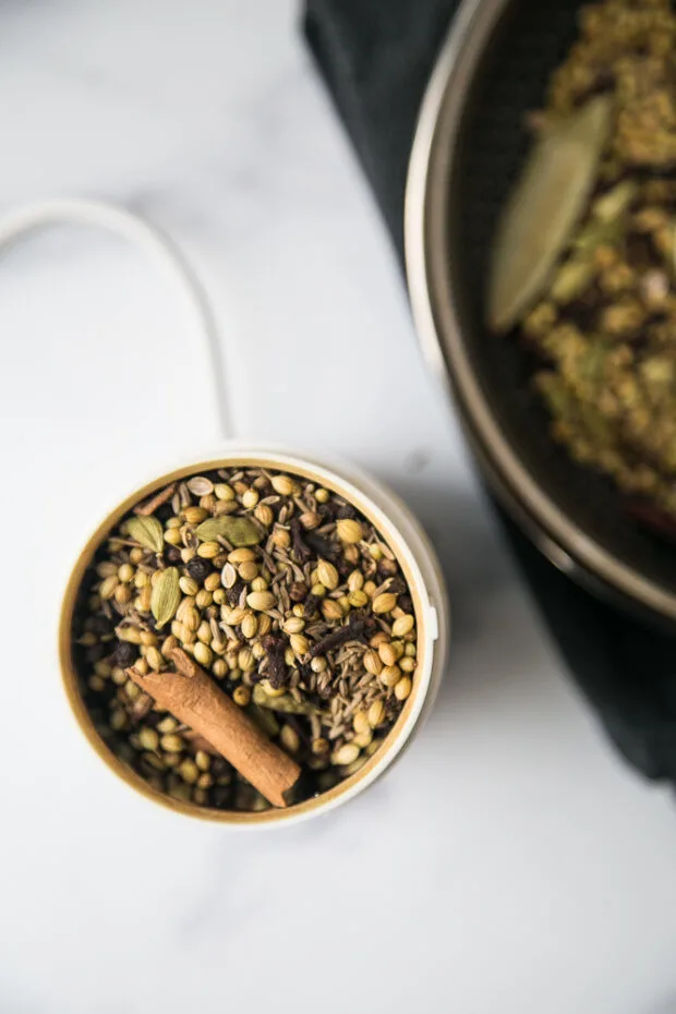 Toasted whole spices in a coffee grinder ready to be ground up.