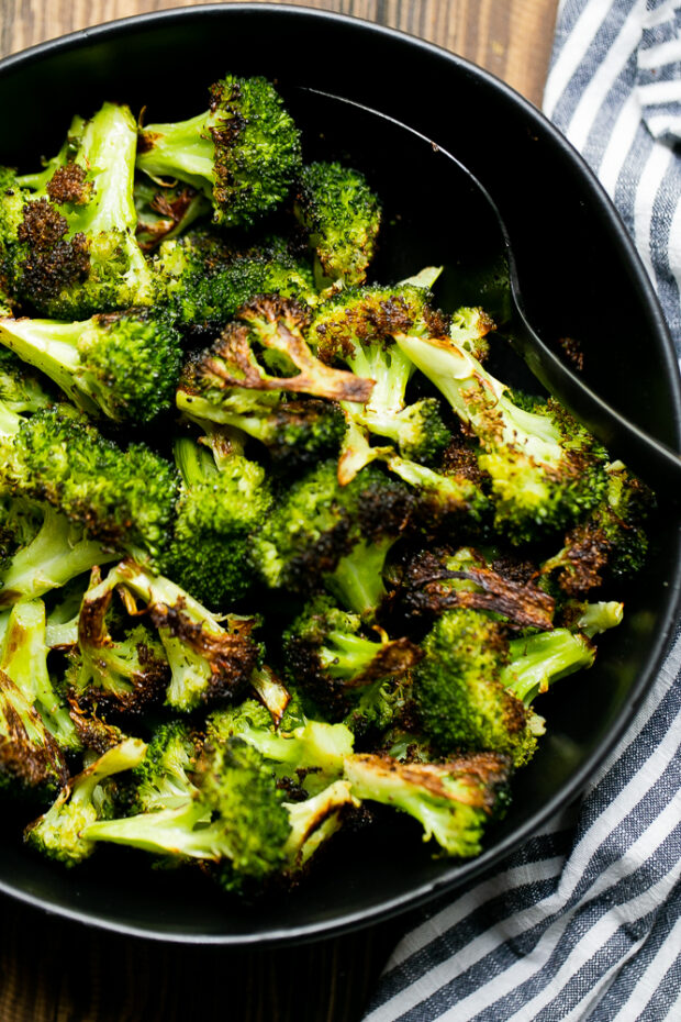 Perfectly roasted and caramelized broccoli in a black serving dish ready to eat.