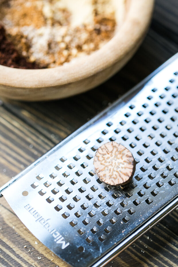 Half of a nutmeg pod sits on a Microplane grater waiting to be grated and used in pumpkin pie spice.