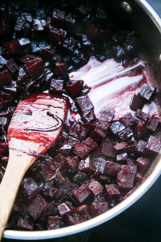 Beets sauteeing in a skillet -- the orange-balsamic glaze has reduced significantly and looks like syrup.