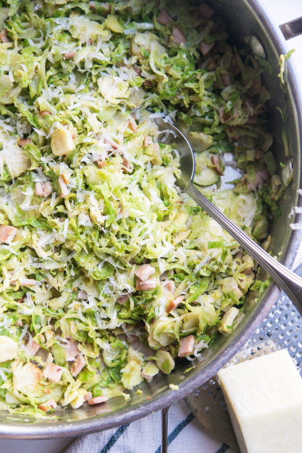 Ham & Brussels Sprout Hash in a large stainless skillet topped with shredded Parmesan cheese.