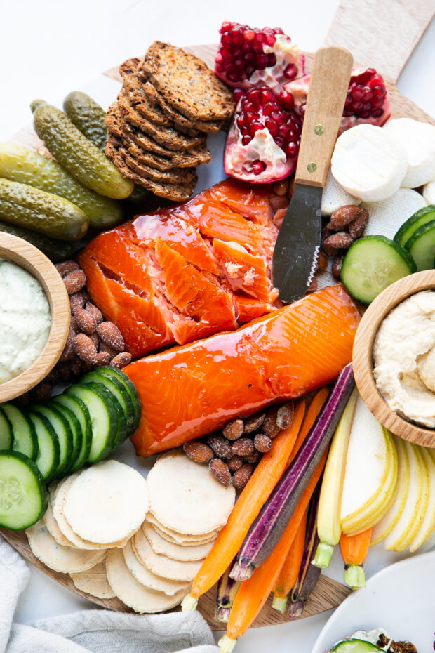 A delicious smoked salmon platter with dips, crackers, fruits, vegetables, and cheeses.
