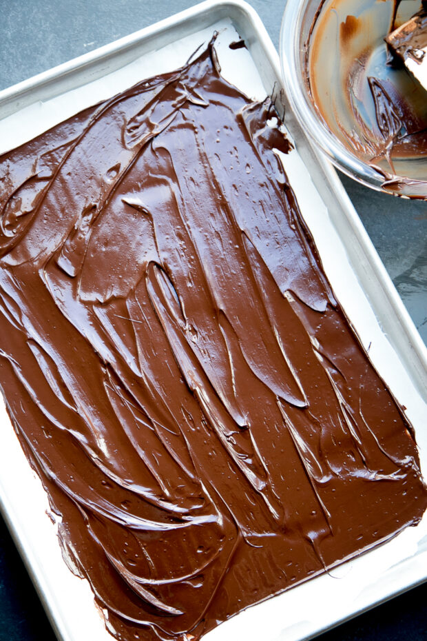 A thin layer of dark chocolate covers a parchment layer.