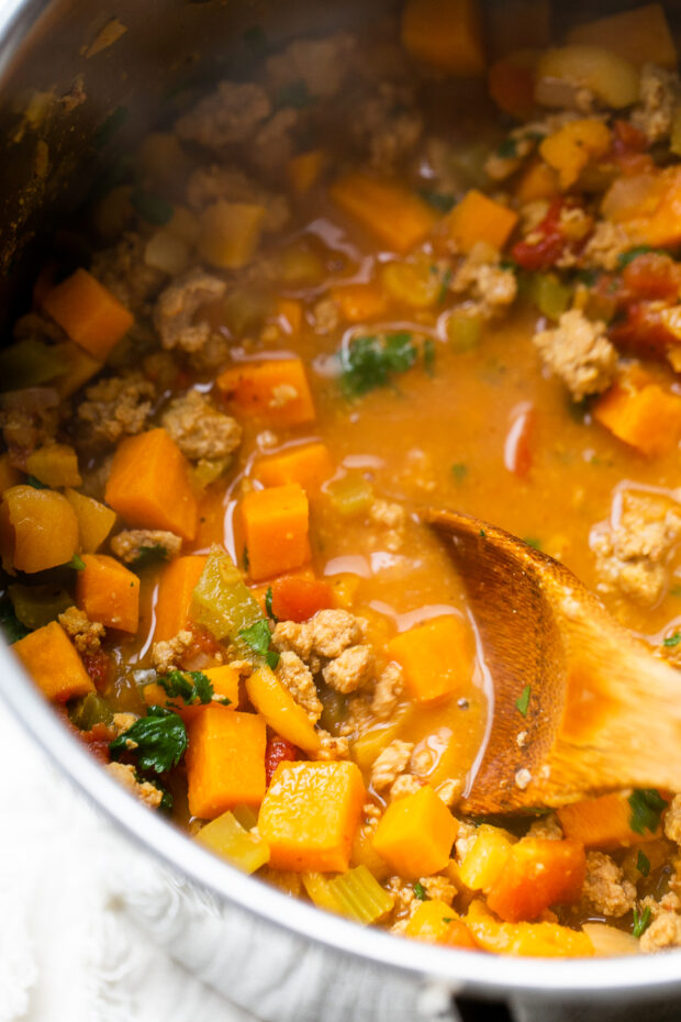 Moroccan Paleo Turkey Chili in a pot being stirred with a wooden spoon.