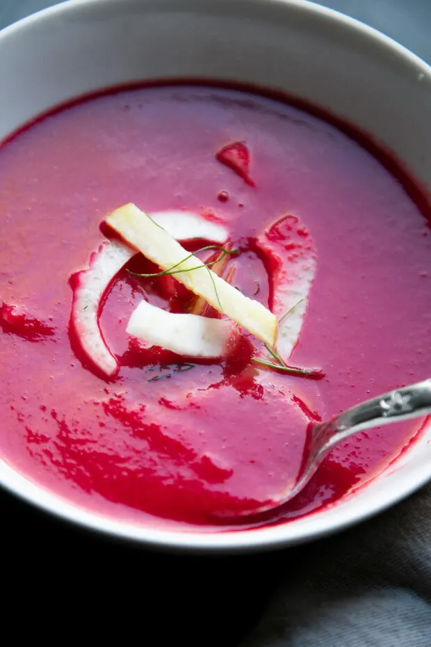 Close up of finished pureed beet soup in a bowl with the apple fennel slaw on top.